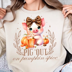 Peut inclure: Un sweat-shirt blanc avec un mignon cochon portant un nœud papillon léopard et tenant un latte à la citrouille épicée. Le texte "Pig Out on Pumpkin Spice" est imprimé sur le sweat-shirt.