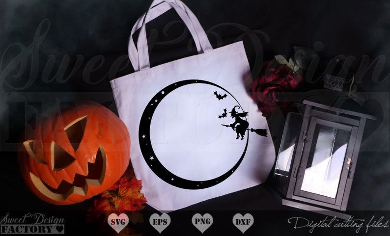 May include: A white tote bag with a black silhouette of a witch flying on a broomstick in front of a crescent moon. The moon is surrounded by stars. The bag is on a black surface with a pumpkin, fall leaves, and a black lantern.