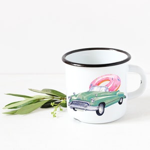 May include: White enamel mug with a black rim featuring a green vintage car with a pink donut on top.