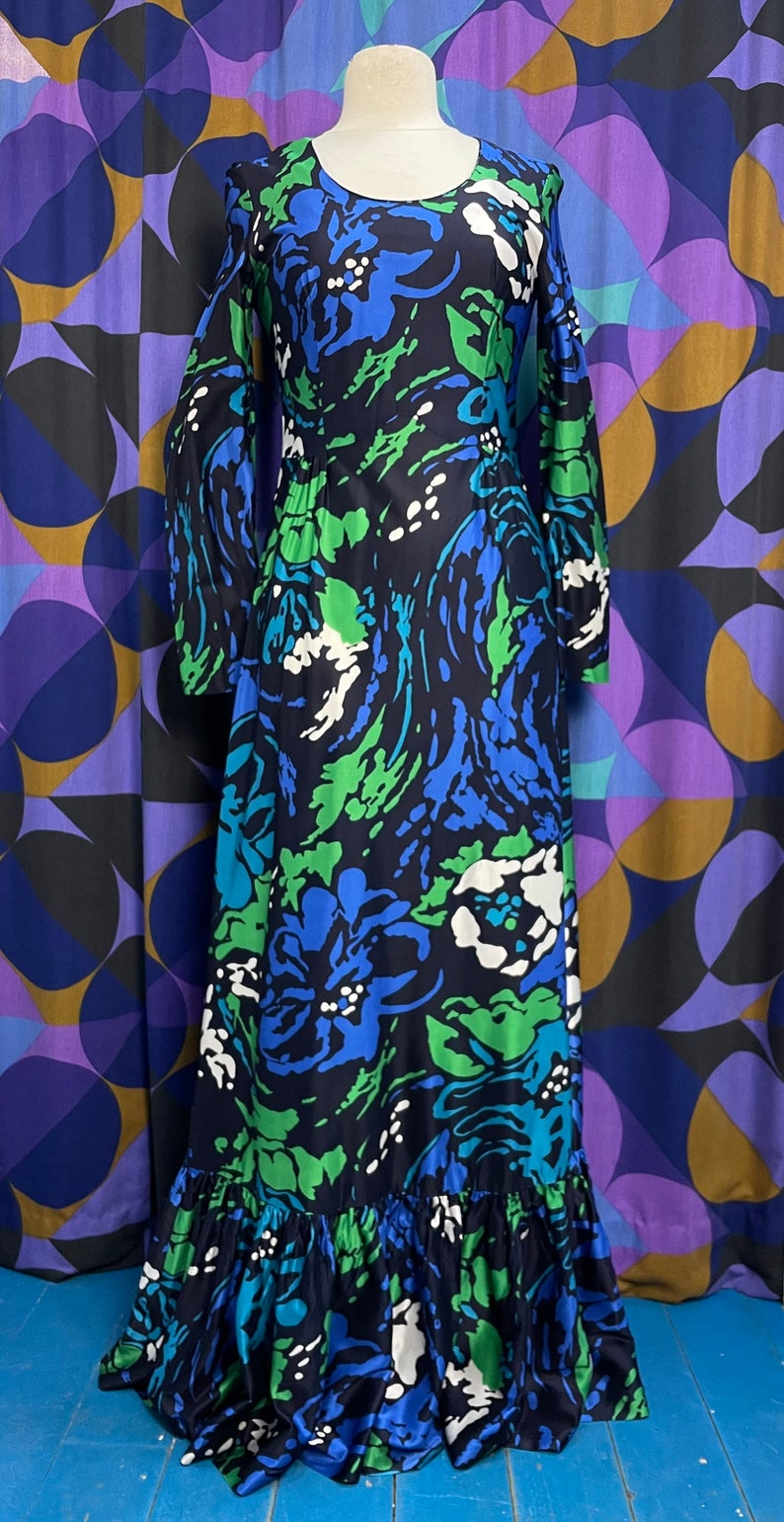 May include: A long-sleeved maxi dress with a floral print in shades of blue, green, and white. The dress has a ruffled hem and a fitted bodice.