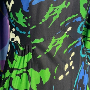 May include: A black dress with a green, blue, and white abstract print. The dress has a fitted bodice and a flowing skirt.