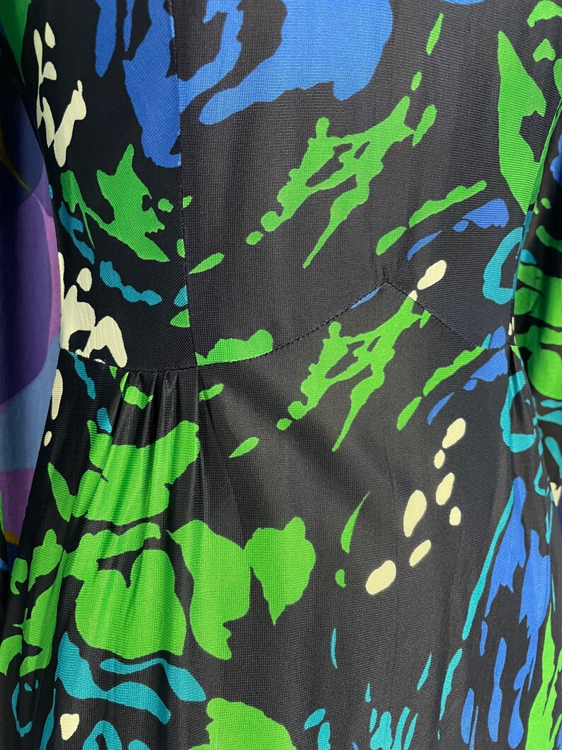 May include: A black dress with a green, blue, and white abstract print. The dress has a fitted bodice and a flowing skirt.