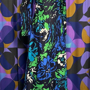 May include: A long-sleeved maxi dress with a black background and a colorful abstract floral print in shades of blue, green, and white. The dress has a ruffled hem.