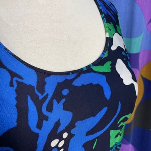 May include: A sleeveless dress with a scoop neck and a blue, green, and white abstract print on a navy background.