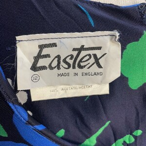 May include: A navy blue dress with a green, blue, and white abstract print. The dress has a label that reads "Eastex Made in England 100% Acetate/Acetat"