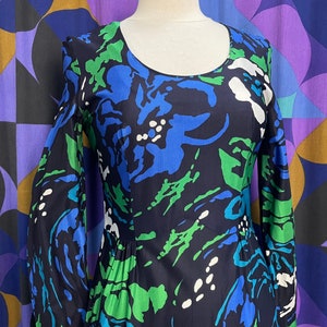 May include: A long-sleeved dress with a blue, green, and white abstract floral print. The dress has a round neckline and a fitted bodice.