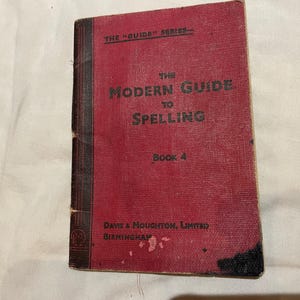 May include: A vintage red book titled "The Modern Guide to Spelling, Book 4." The cover features the text in white, with "The Guide Series" at the top. The book is from Davis & Moughton, Limited, Birmingham.