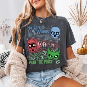 May include: Dark gray t-shirt with a graphic design featuring the text "No Safe Words" and "Off Limits." The design includes a blue skull, a red helmet, and a green monster face. The phrase "Paid the Price" is also included.
