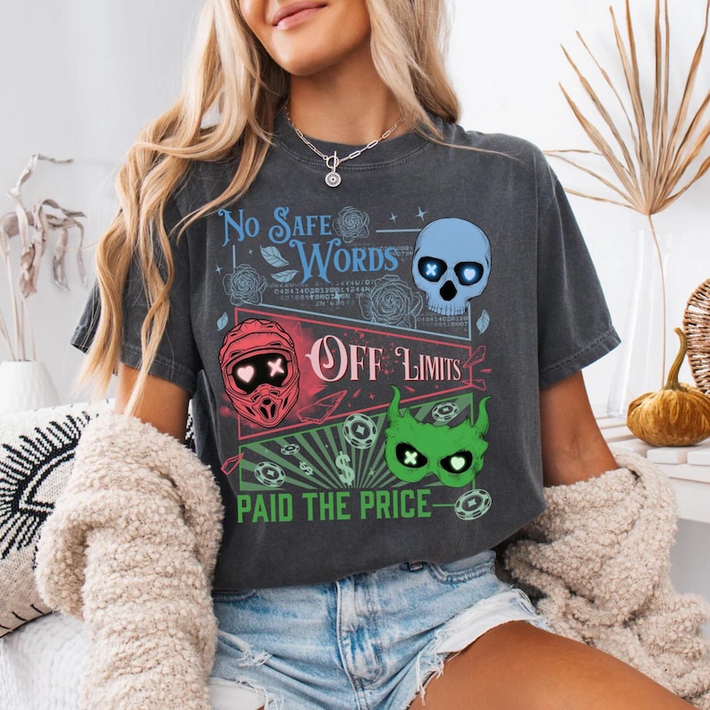 May include: Dark gray t-shirt with a graphic design featuring the text "No Safe Words" and "Off Limits." The design includes a blue skull, a red helmet, and a green monster face. The phrase "Paid the Price" is also included.
