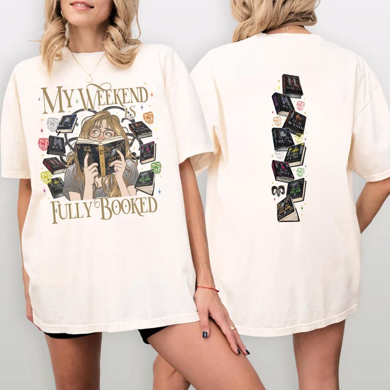 Pu&ograve; includere: T-shirt color crema con la scritta "My Weekend is Fully Booked" e una grafica di una persona che legge circondata da libri. Il retro della maglietta presenta una pila verticale di libri illustrati.