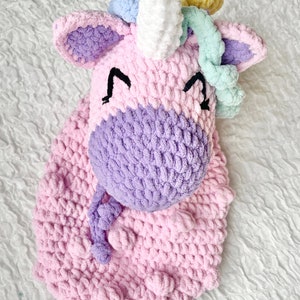 May include: A crocheted unicorn head with a pink and purple body, white horn, and rainbow colored mane.