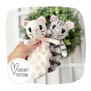 May include: Two crocheted cat toys. One is white with a pink bow, the other is gray and white. Both have pink inner ears and black facial details. The image includes the text "Crochet Pattern" inside a heart.