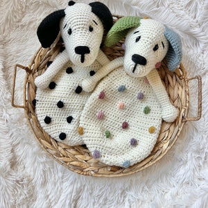 May include: Two crocheted dog-shaped baby blankets in a wicker basket. One blanket is white with colorful polka dots and the other is white with black polka dots.
