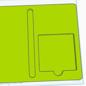 May include: A lime green rectangular object with a long, thin, vertical cutout on the left side and a square cutout with a curved bottom on the right side. The object has a light blue border and the word "inches" is visible.