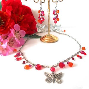 Schmuckset aus baumelnden Cluster-Ohrringen und Halskette mit Schmetterlingsanhängern und orangefarbenen, roten und fuchsiafarbenen Perlen