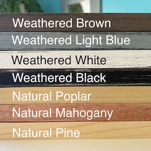 Puede incluir: Primer plano de siete muestras de marcos de madera diferentes. Los marcos est&aacute;n dispuestos verticalmente, con el marco superior en marr&oacute;n desgastado, seguido de azul claro desgastado, blanco desgastado, negro desgastado, &aacute;lamo natural, caoba natural y pino natural.