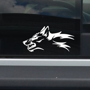 May include: A white vinyl sticker of a wolf's head with a stylized design. The wolf is facing to the right and has a fierce expression.