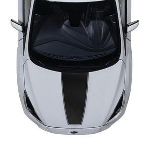 May include: A white car with a black racing stripe down the hood. The car is viewed from above, showing the front of the vehicle.