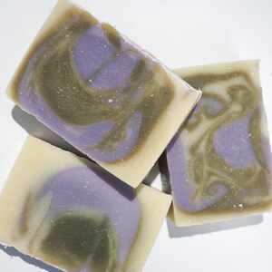 May include: Three bars of handmade soap with a swirl pattern of green, purple, and white.