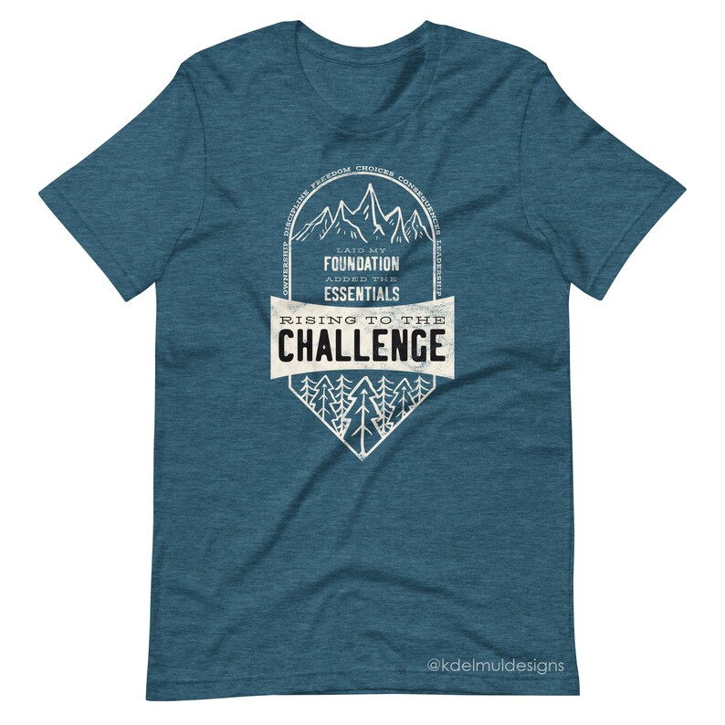 K&ouml;nnte beinhalten: Tealblaues T-Shirt mit einem wei&szlig;en Grafikdesign einer Bergkette mit dem Text "Laid my foundation, added the essentials, Rising to the challenge".
