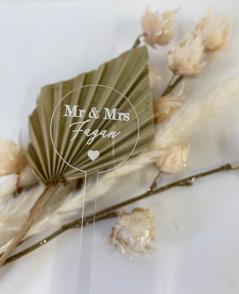 May include: A clear acrylic wedding sign with the text "Mr & Mrs Fagan" and a small heart.