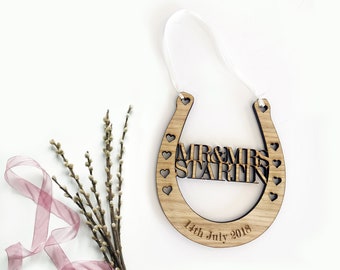 May include: Wooden horseshoe ornament with the text "MR & MRS STARLIN" and the date "14th July 2018" engraved on it. The horseshoe is decorated with small hearts.