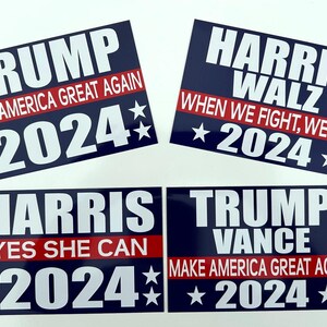 May include: Four blue and red political campaign signs with white text. The signs feature the names "Trump", "Harris", and "Walz" with the year "2024" and slogans such as "Make America Great Again" and "When We Fight, We Win".