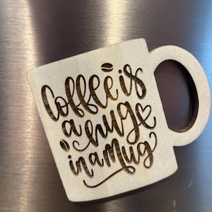 May include: A wooden coffee mug with the text "Coffee is a hug in a mug" engraved on it.