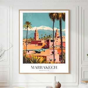 Peut inclure: Une affiche encadrée représentant une illustration colorée de Marrakech, au Maroc. L'œuvre d'art dépeint un paysage urbain avec des bâtiments roses et oranges, des palmiers et des montagnes enneigées en arrière-plan. Le texte "MARRAKECH MOROCCO" est affiché en bas.