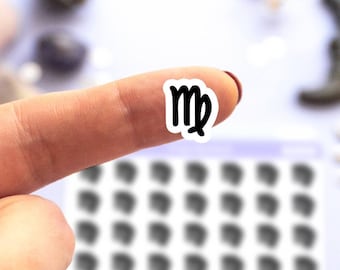 May include: A finger holding a white sticker with a black Virgo zodiac symbol. The sticker is on a white background with a sheet of stickers in the background.