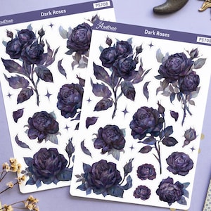 Peut inclure: Deux planches d'autocollants avec des illustrations de roses violet foncé, intitulées "Dark Roses" et "Astrale". L'image comprend également des cartes de tarot, des cristaux, une bougie et des décorations célestes.