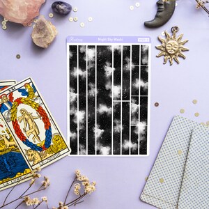 May include: A sheet of black and white washi tape with a night sky design featuring clouds and stars. The tape is labeled "Night Sky Washi" and "WS010".