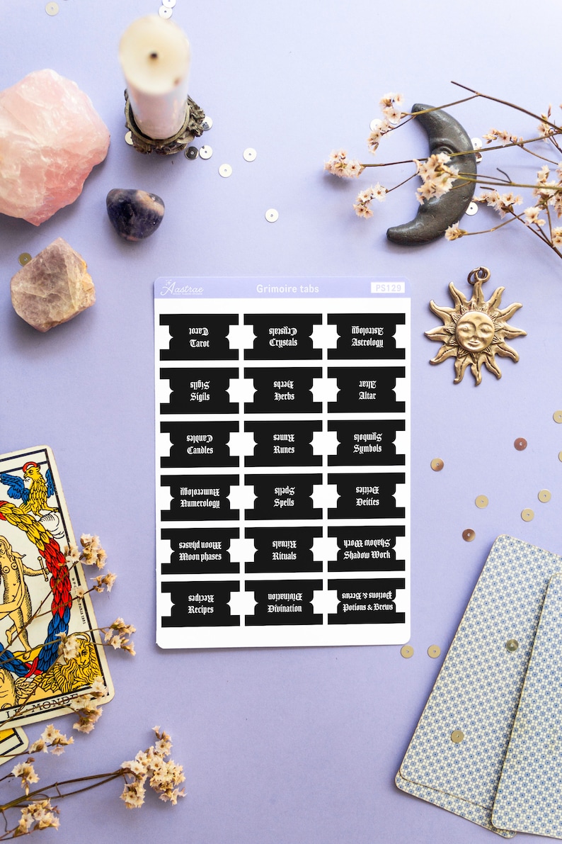 May include: A sheet of black and white stickers with gothic font text. The stickers are labeled with various topics related to witchcraft, such as tarot, crystals, astrology, sigils, herbs, altar, candles, runes, symbols, numerology, spells, deities, moon phases, rituals, shadow work, recipes, divination, and potions and brews.