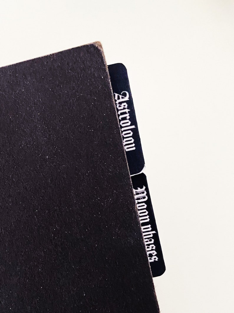 May include: Black notebook with two black index tabs labeled "Astrology" and "Moon Phases".