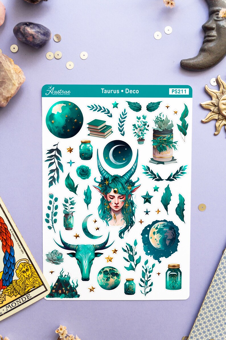 May include: A sheet of stickers featuring a green and gold Taurus zodiac sign with a crescent moon, stars, and plants. The stickers are labelled "Taurus Deco" and "PS211".