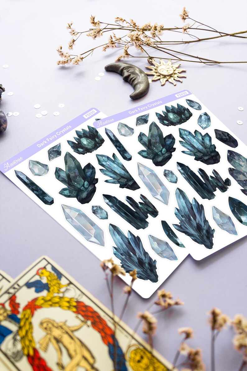 May include: Two sheets of stickers featuring watercolor illustrations of dark blue and clear crystals. The stickers are labeled "Dark Fairy Crystals" and include the brand name "Astron". Decorative elements include dried flowers, a crescent moon, and a sun charm.