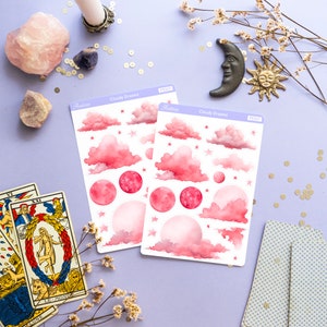 May include: Two sheets of pink and white watercolor stickers with clouds, stars, and moons. The stickers are labeled "Cloudy Dreams" and have a product number.