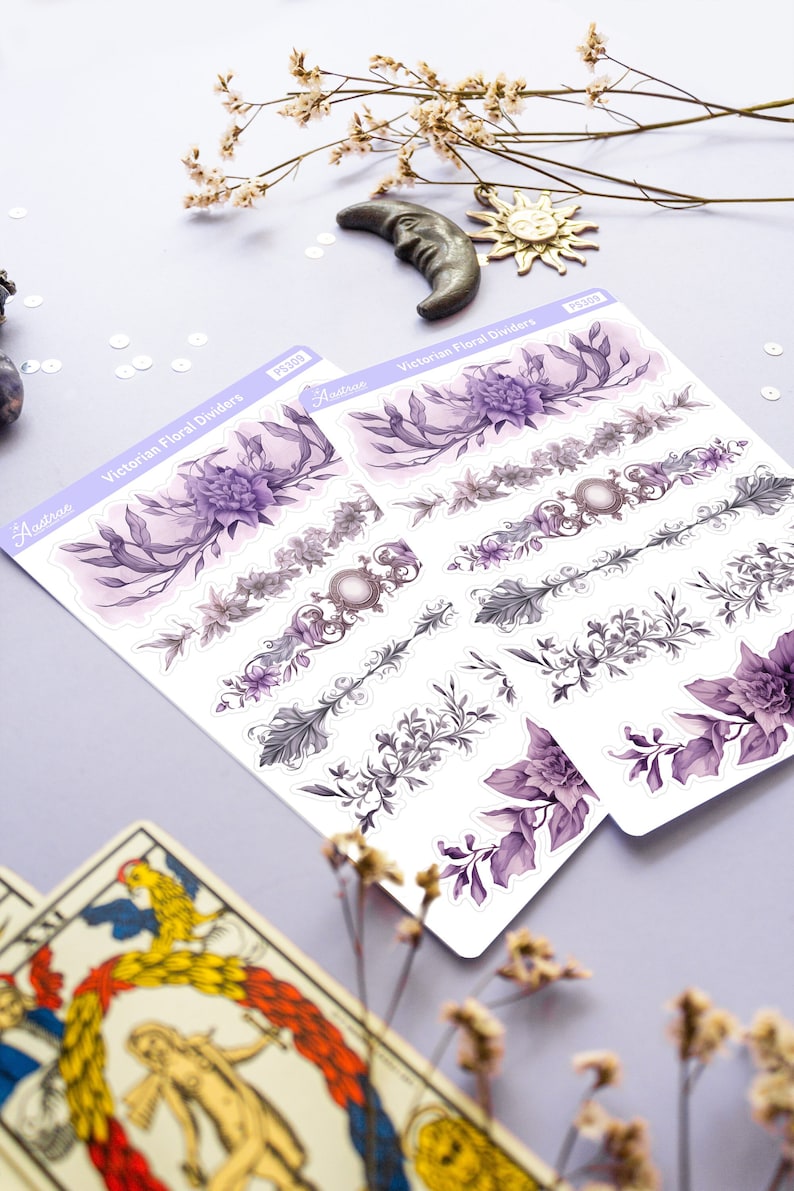 Peut inclure: Deux feuilles d'autocollants avec des s&eacute;parateurs floraux victoriens. Les autocollants sont blancs avec des motifs floraux violets et gris. Le texte "Victorian Floral Dividers" est imprim&eacute; sur les feuilles.