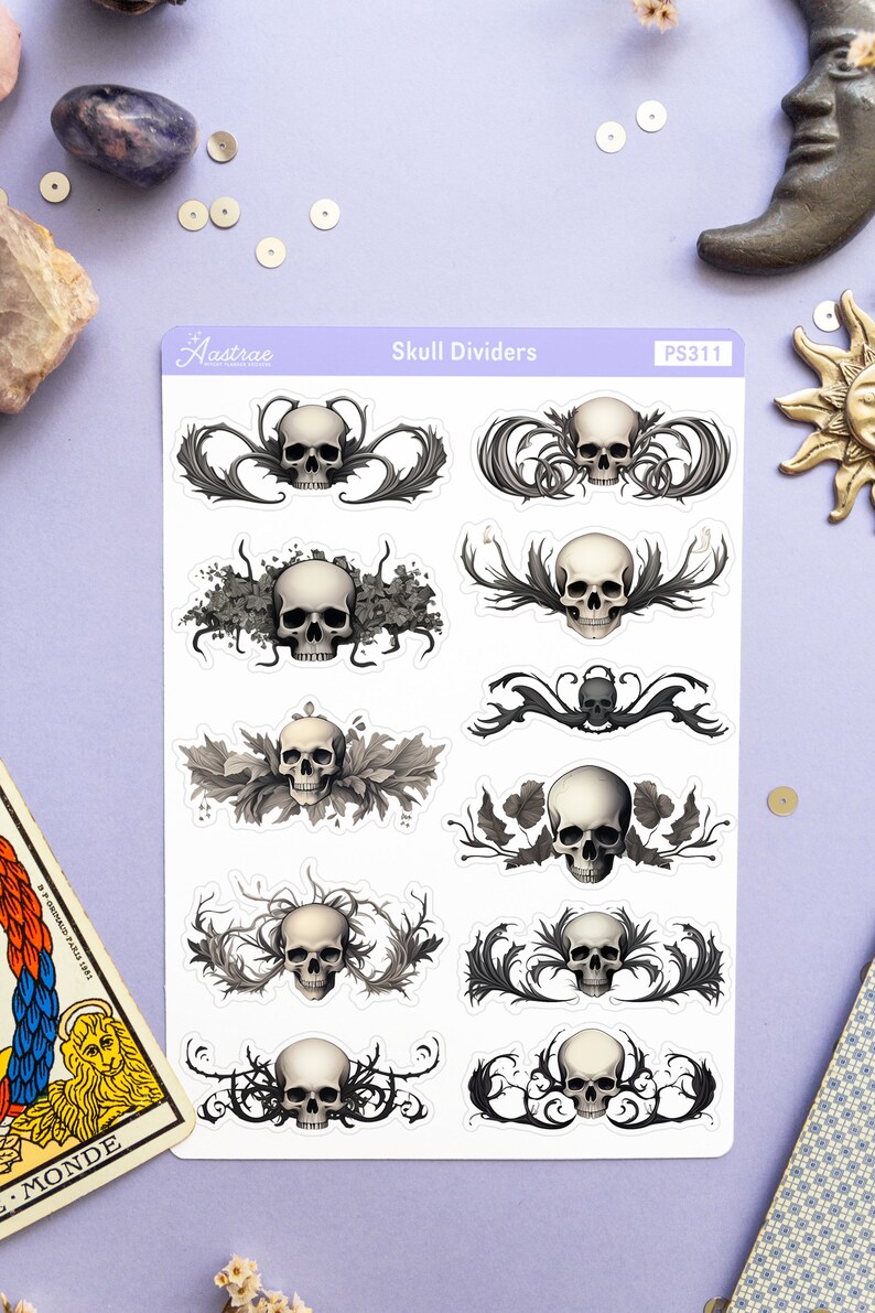 May include: A sheet of skull divider stickers with a white background and black and gray skulls with intricate floral designs. The sheet is labeled "Skull Dividers" and "PS311".