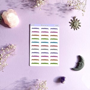 May include: A sheet of colorful stickers with the word "meditation" written in different colors and styles. The stickers are arranged in rows of three. There are also stickers of a sun and a moon.