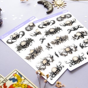 May include: Two sheets of stickers with a skull and floral design. The stickers are white with black and gray details. The text on the stickers reads "Skull Dividers" and "Aestrea".