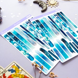 May include: Two sheets of blue watercolor washi tape with a starry sky and cloud design. The washi tape is labeled "Blue Wash" and "Audtree".