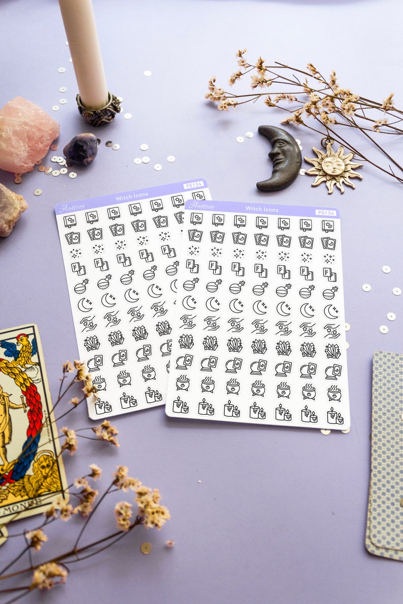 May include: Two sheets of white sticker paper with black witch-themed icons. The icons include a cauldron, a moon, a crystal, a book, a candle, and a hand holding a crystal. The sticker sheets are labeled "Witch Icons" and "PS134".