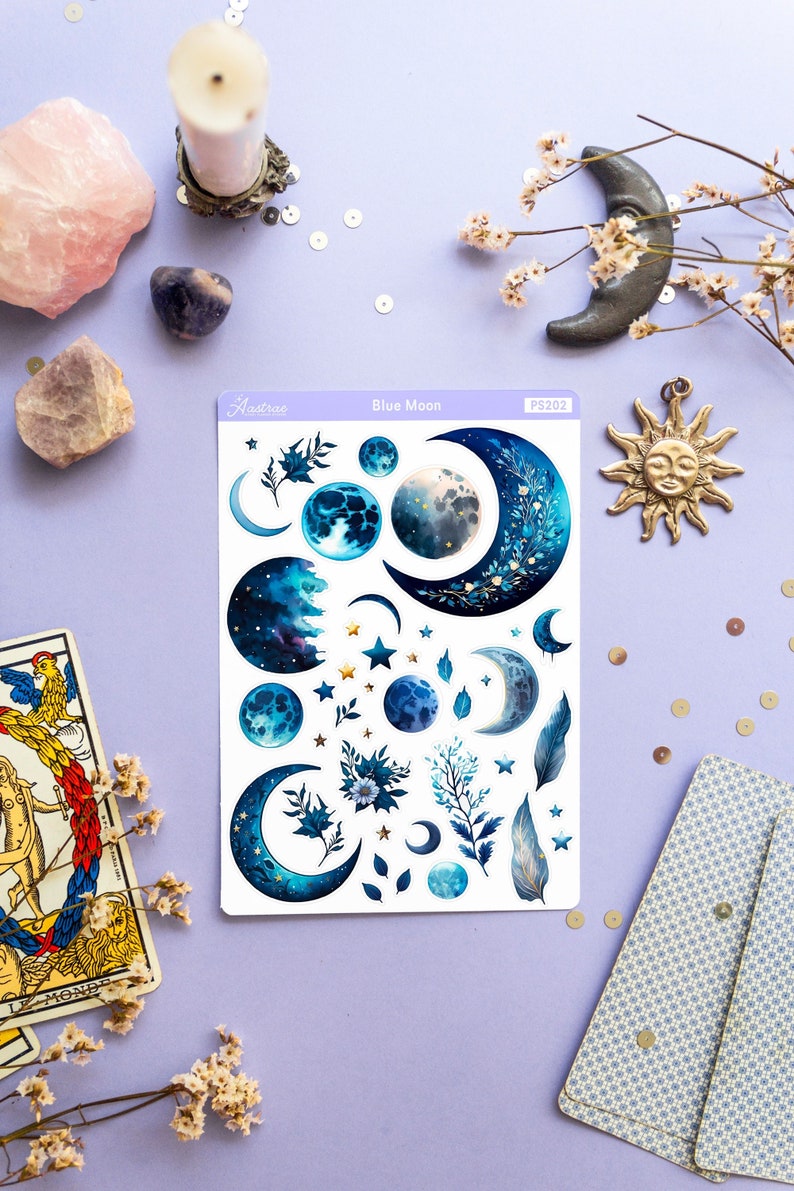May include: A sheet of blue moon themed stickers with various crescent moons, full moons, and stars. The stickers are on a white background and have a blue, gold, and white color scheme. The sheet is labeled "Blue Moon" and "PS202".