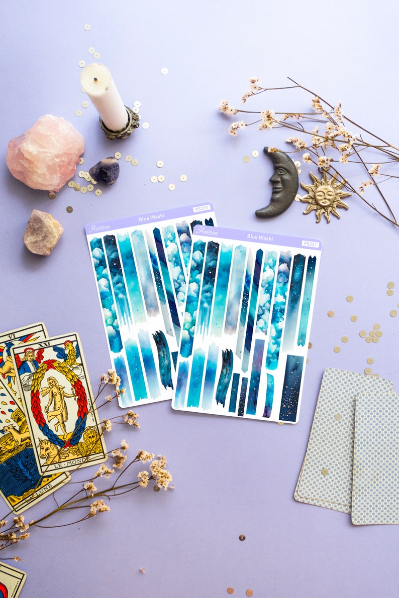 May include: Two sheets of blue and white washi tape with a galaxy design. The tape is labeled "Blue Wash" and has the product number PS2231.