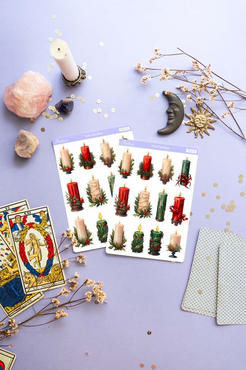 May include: Two sheets of stickers featuring illustrations of Yule candles. The stickers are on a purple background with gold glitter, tarot cards, and a white candle in a silver holder. The stickers are labeled "Yule Candles" and have the product number "PS315".