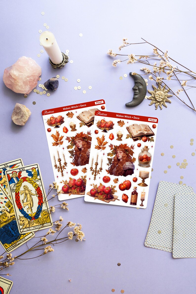 May include: Two sheets of stickers featuring a witch with red hair and a crown of leaves, surrounded by autumnal elements like apples, candles, and a book. The stickers are labeled "Mabon Witch + Deco" and "Astr&eacute;e" with the product number "PS467".
