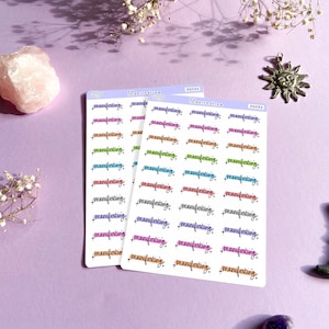 Puede incluir: Tres hojas de pegatinas con la palabra "manifesting" escrita en diferentes colores y estilos. Las pegatinas est&aacute;n sobre un fondo morado.