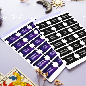 May include: Two sheets of stickers with a galaxy background and black text. The stickers are labeled with various topics related to witchcraft, such as "Tarot", "Crystals", "Sigils", "Spells", "Herbs", "Candles", "Runes", "Numerology", "Moon Phases", "Rituals", "Symbols", "Deities", and "Recipes".