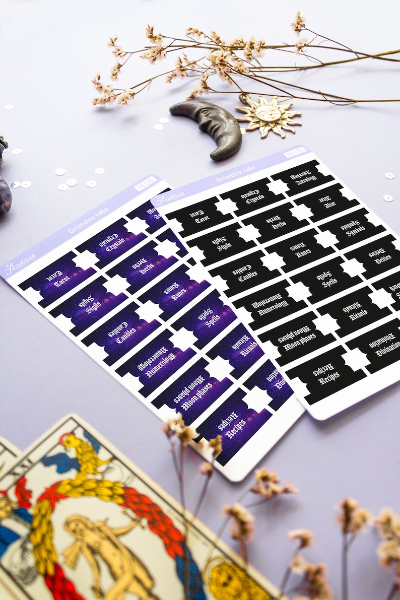 May include: Two sheets of stickers with a galaxy background and black text. The stickers are labeled with various topics related to witchcraft, such as "Tarot", "Crystals", "Sigils", "Spells", "Herbs", "Candles", "Runes", "Numerology", "Moon Phases", "Rituals", "Symbols", "Deities", and "Recipes".